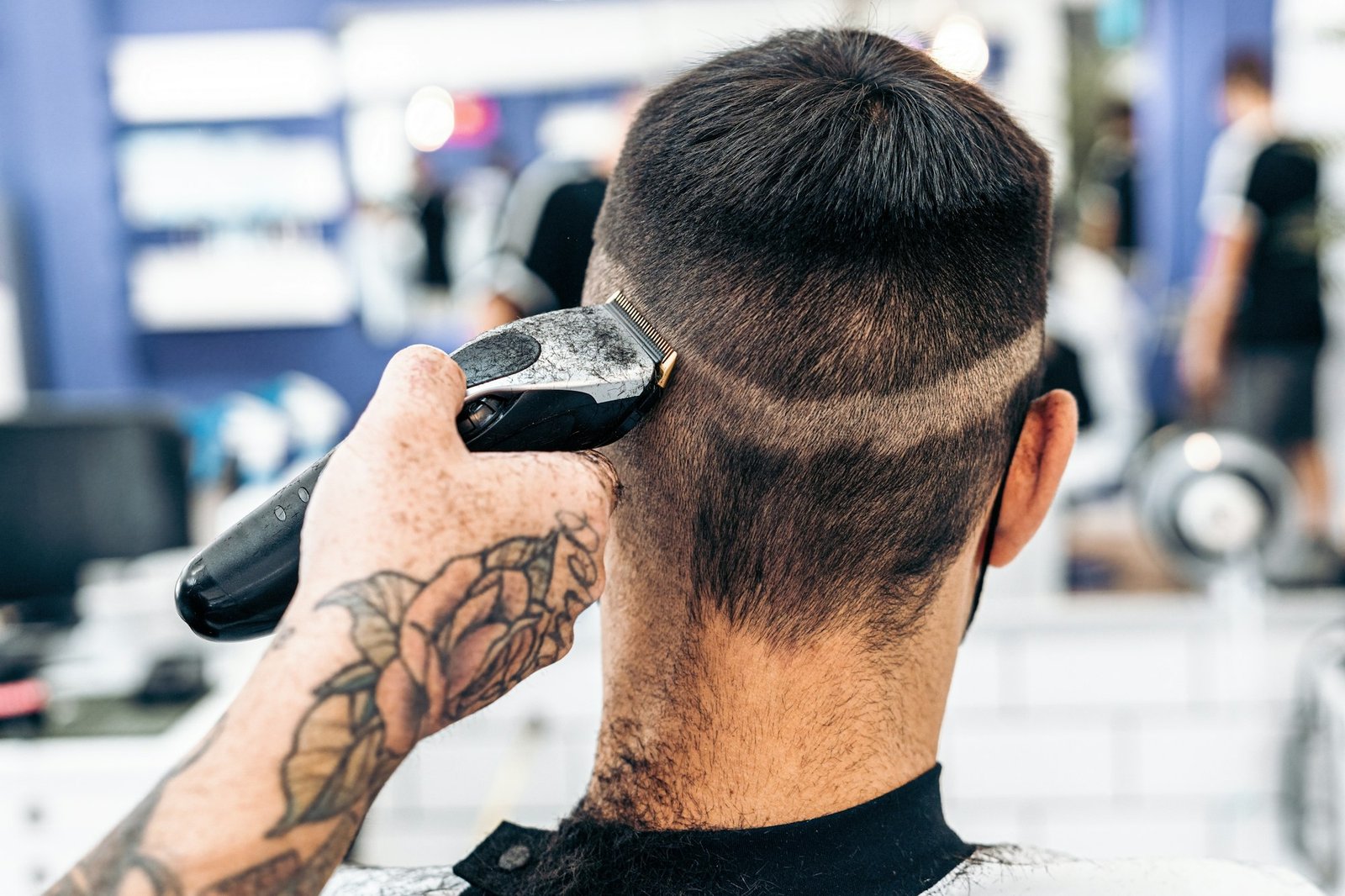 Barber shaving the back of the head of a man with an electric machine in a salon